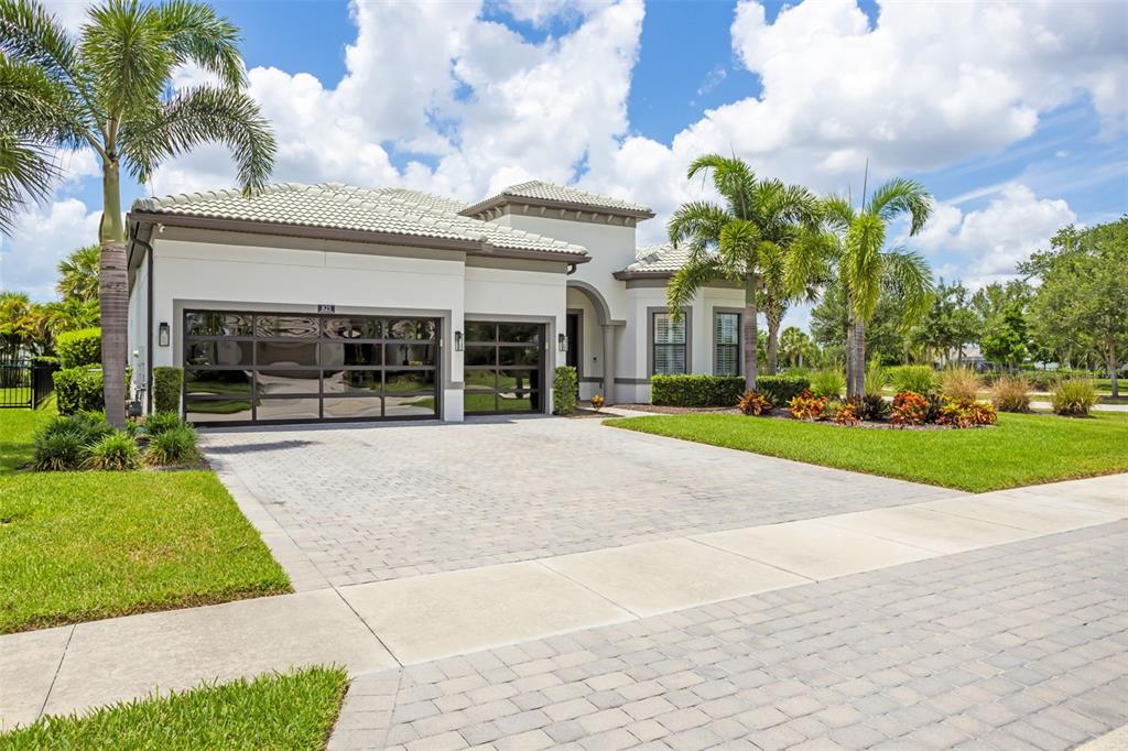 A single-story house with a paved driveway, three-car garage, and palm trees in the yard — 825 SEASCAPE PLACE, SARASOTA, FL