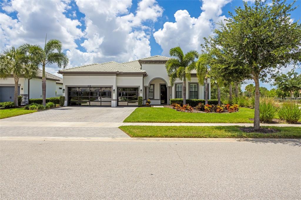 A single-story house with a paved driveway, two-car garage, and palm trees in the yard — 825 SEASCAPE PLACE, SARASOTA, FL