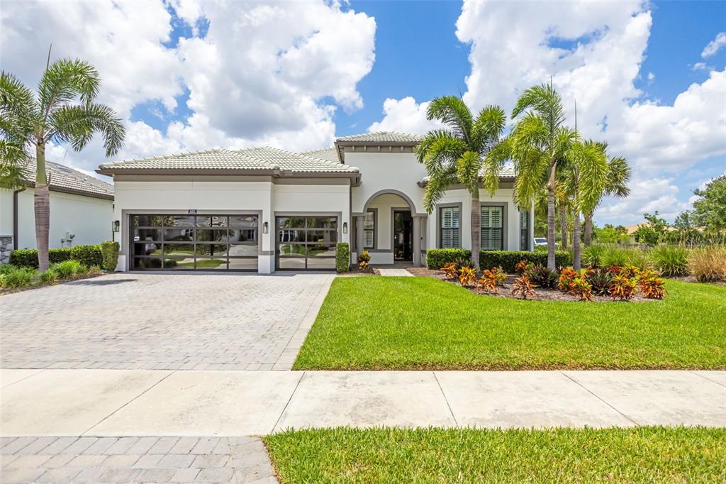 A single-story house with a paved driveway, glass-paneled garage doors, and palm trees — 825 SEASCAPE PLACE, SARASOTA, FL