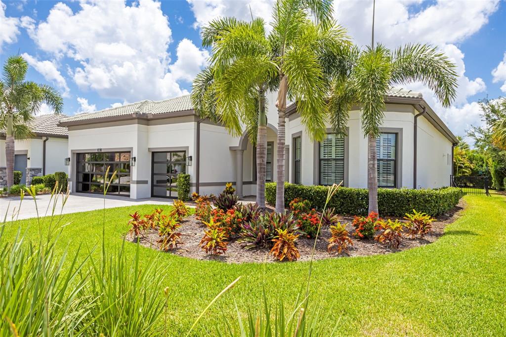 A single-story house with a white exterior, a multi-car garage, and a landscaped front garden — 825 SEASCAPE PLACE, SARASOTA, FL