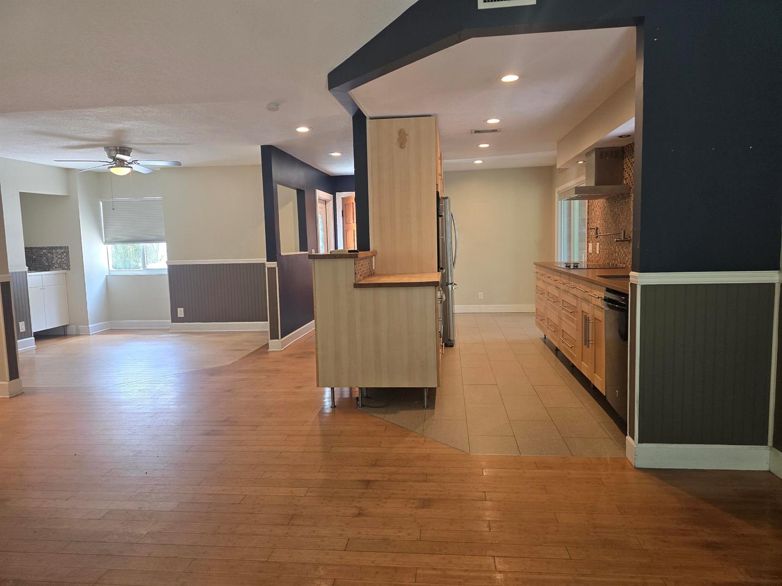 An open-concept kitchen with light wood cabinets and tile flooring transitions to a living area — 18162 Jupiter Landings Drive, Jupiter FL 33458, JUPITER, FL