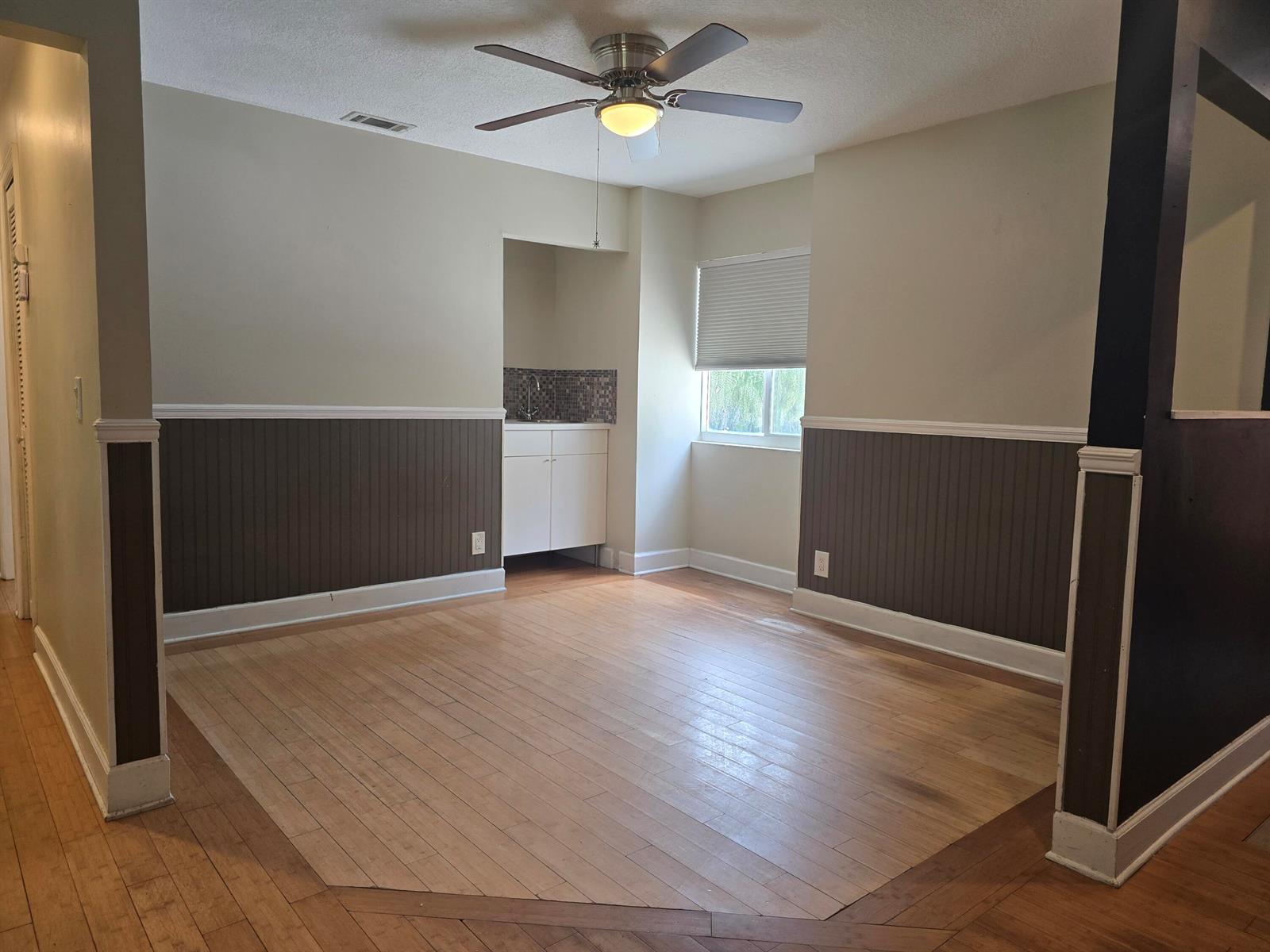 A dining room features light wood flooring, dark wainscoting, a ceiling fan, and a wet bar — 18162 Jupiter Landings Drive, Jupiter FL 33458, JUPITER, FL