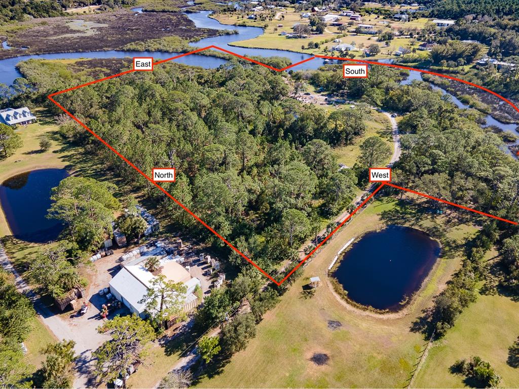 An aerial view shows a wooded lot outlined in red, adjacent to ponds and a building — TUMBLIN DRIVE, NEW SMYRNA BEACH, FL