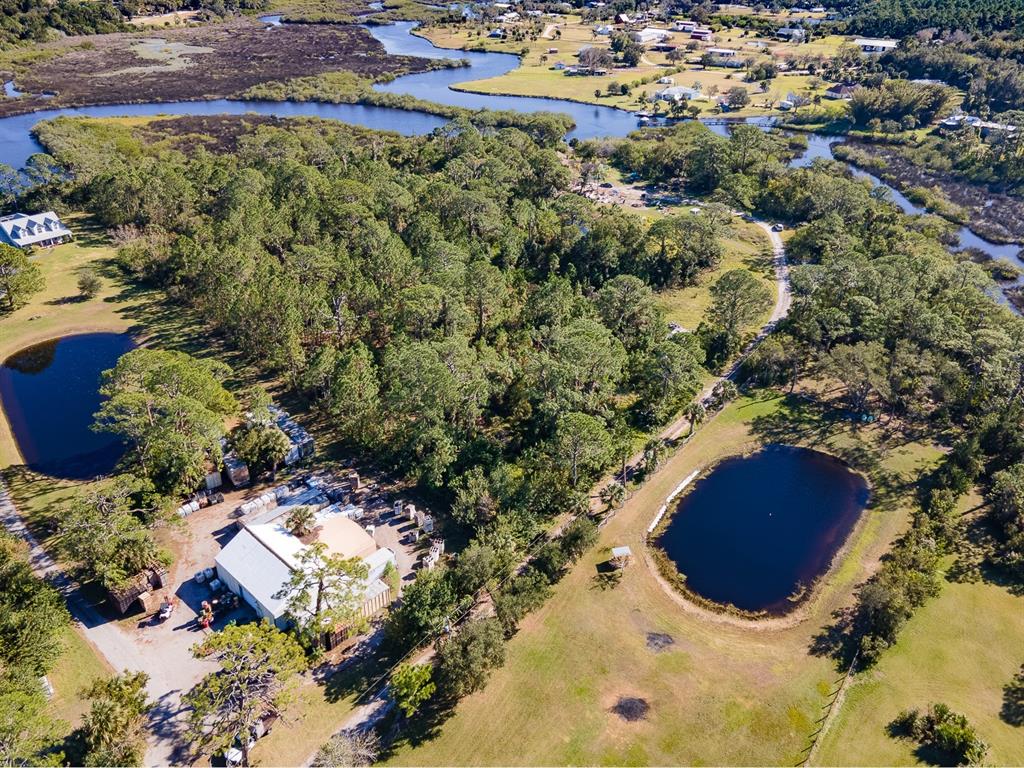 An aerial view shows a rural property with a warehouse, two ponds, and surrounding woods — TUMBLIN DRIVE, NEW SMYRNA BEACH, FL