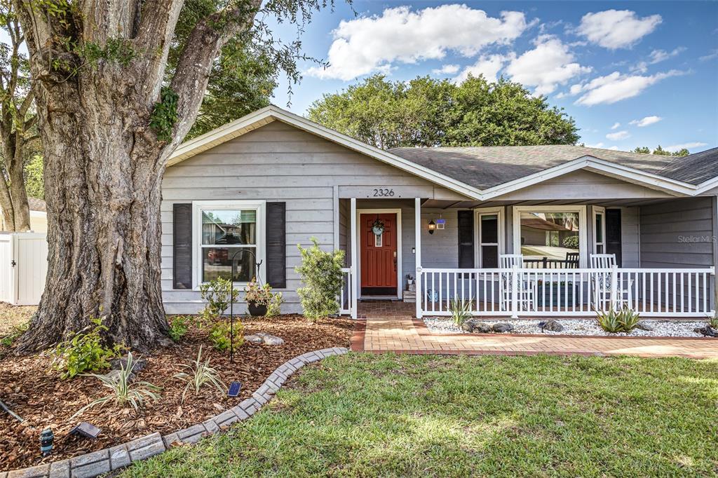 A single-story house with gray siding, a red front door, and a large tree — 2326 ARROWHEAD BOULEVARD, LAKELAND, FL