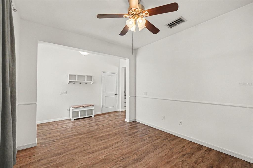 A spacious living area features wood-look flooring, a ceiling fan, and sliding glass patio doors — 12324 STREAMBED DRIVE, RIVERVIEW, FL