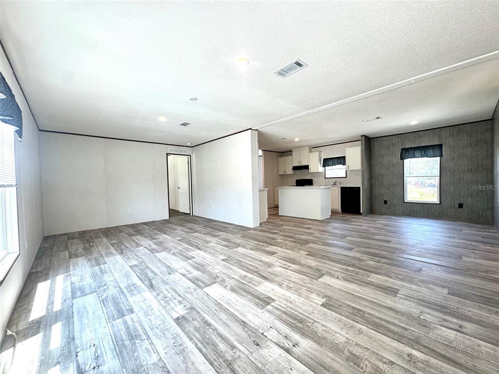An open-concept living area features light wood-look flooring, white walls, and a kitchen with white cabinetry — 389 WATERVIEW DRIVE, POLK CITY, FL