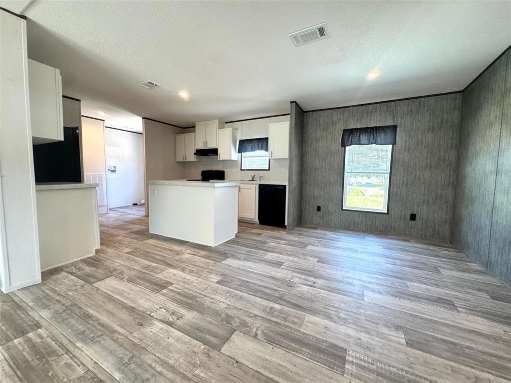 An open-concept kitchen and living area featuring white cabinets, a central island, and wood-look flooring — 389 WATERVIEW DRIVE, POLK CITY, FL