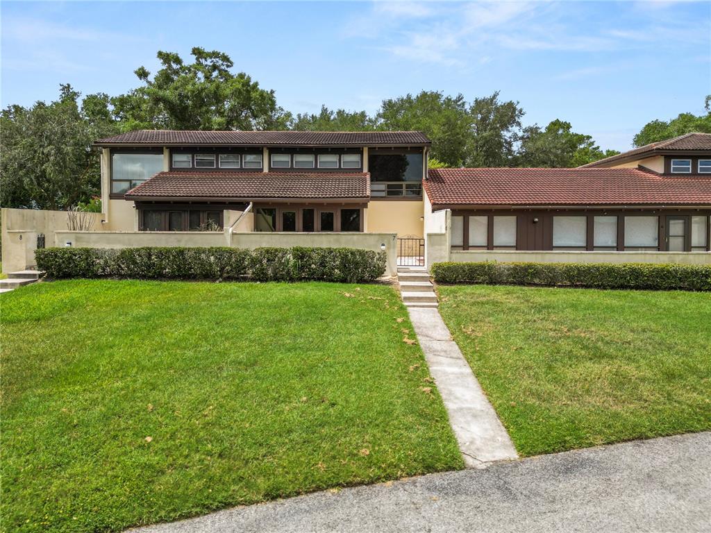 An exterior view of a two-story townhouse with a red tile roof and courtyard — 7 LOMA LINDA UNIT 7, LAKELAND, FL