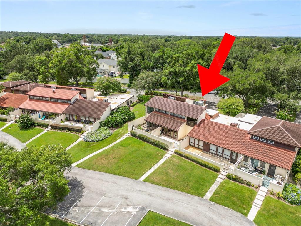 An aerial view shows a two-story townhouse with a brown tile roof and a red arrow — 7 LOMA LINDA UNIT 7, LAKELAND, FL