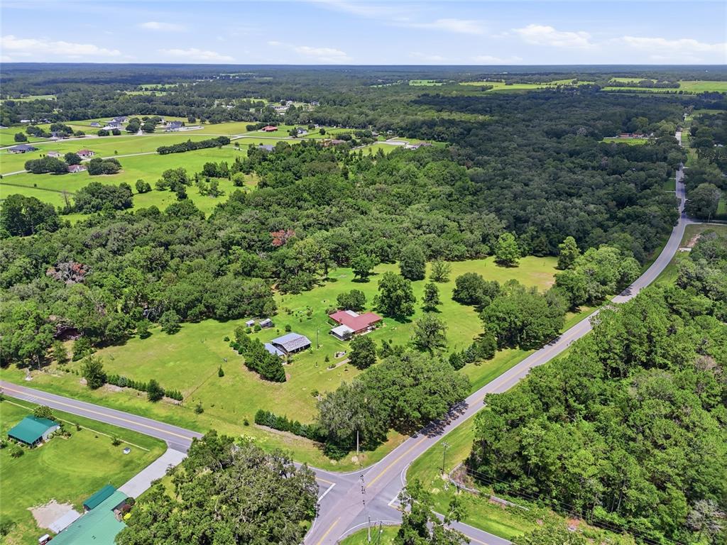 An aerial view shows a rural property with a house, outbuilding, and surrounding green fields — 4875 SW COUNTY ROAD 240, LAKE CITY, FL