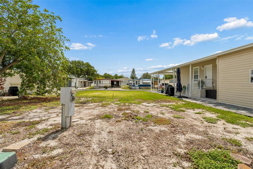 A view of a sandy yard between two mobile homes under a bright blue sky — 9790 66TH STREET N UNIT 210, PINELLAS PARK, FL