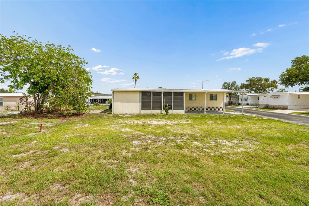 A single-story mobile home with a screened-in porch sits on a grassy lot — 9790 66TH STREET N UNIT 210, PINELLAS PARK, FL