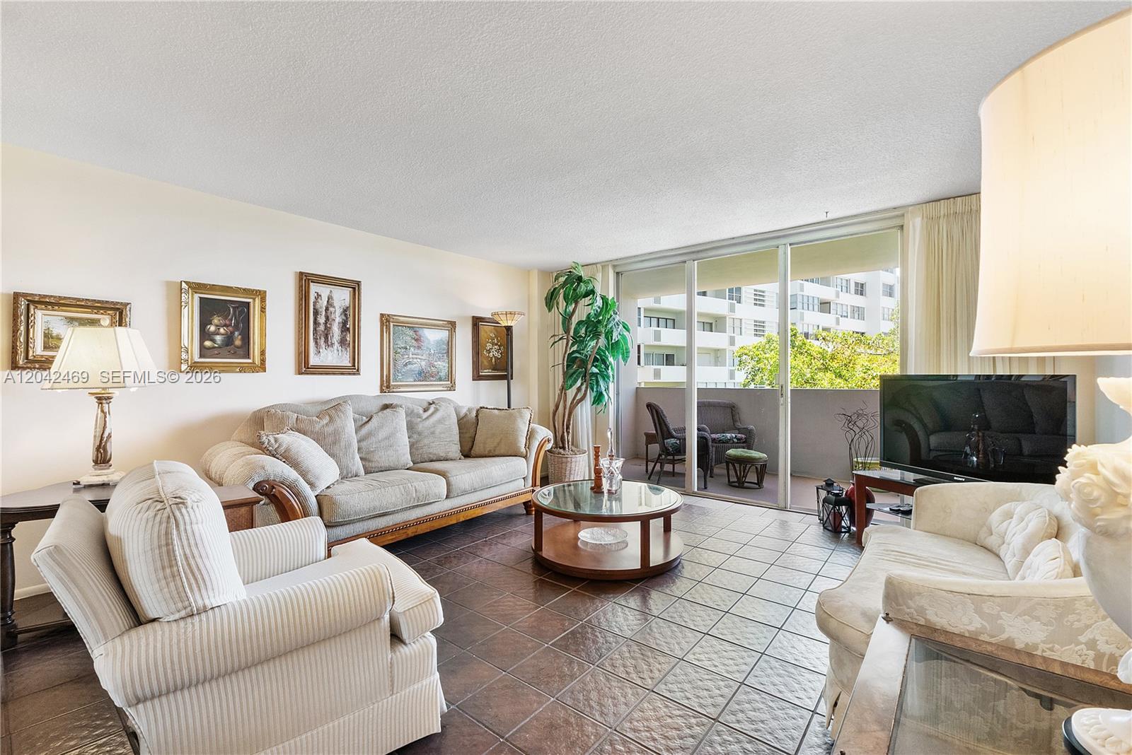A living room features tiled floors, a beige sofa, armchairs, and a balcony with seating — 5 Island Ave # 6A, Miami Beach FL 33139, MIAMI BEACH, FL
