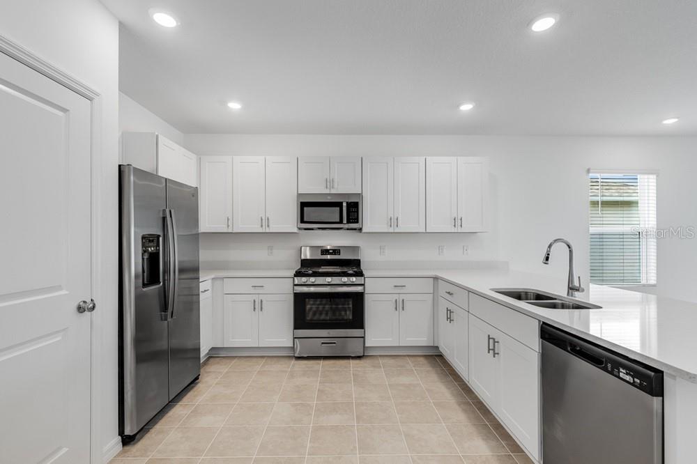 A kitchen with white cabinets, stainless steel appliances, and a peninsula island — 13803 SHELLMORE AVENUE, PALMETTO, FL