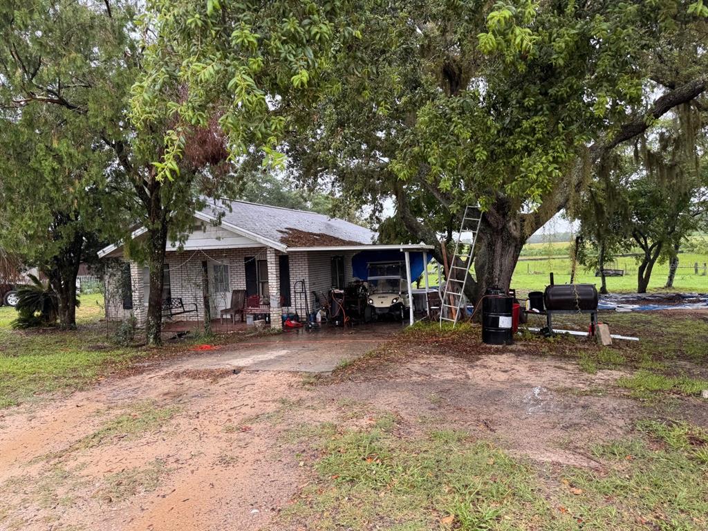 A single-story brick house with a carport, a golf cart, and large trees in front — 4011 E ROBINSON DRIVE, HAINES CITY, FL