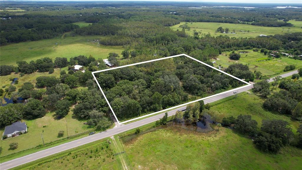 An aerial view shows a rectangular wooded lot outlined in white next to a road — 5804 STATE ROAD 33, CLERMONT, FL
