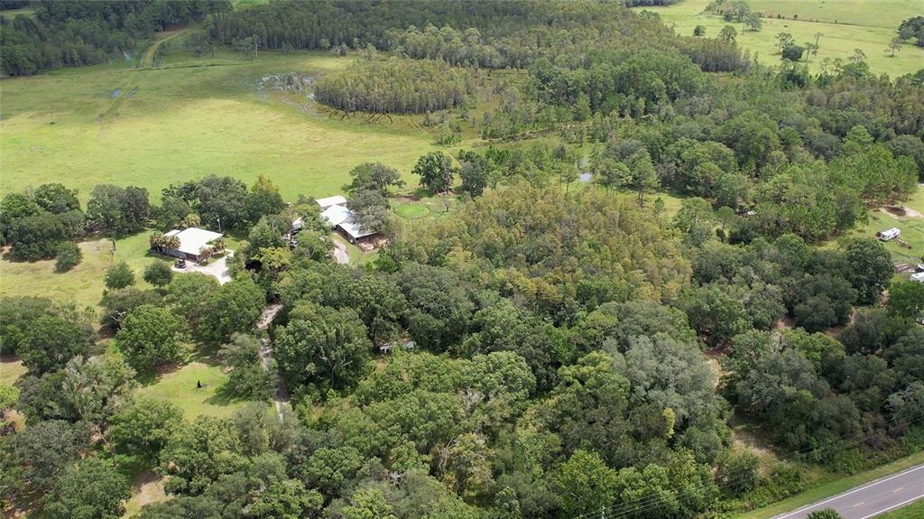 An aerial view shows a house and outbuildings surrounded by trees and open pasture land — 5804 STATE ROAD 33, CLERMONT, FL