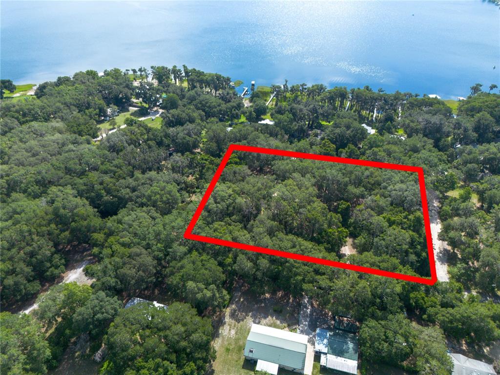 An aerial view shows a wooded lot outlined in red near a lake — 7517 NE 221ST STREET, MELROSE, FL