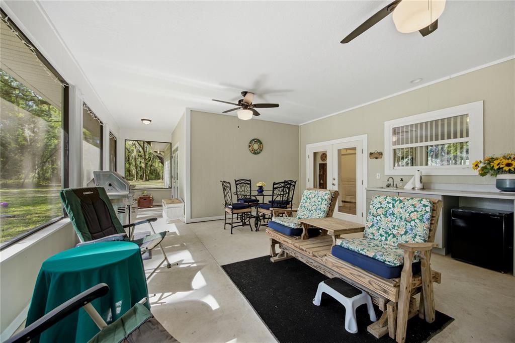 A screened-in patio features a dining set, a wooden bench, and a small outdoor kitchen — 7517 NE 221ST STREET, MELROSE, FL
