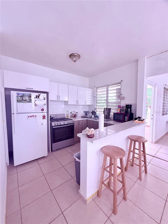 A living room features a green sectional sofa, a television on a stand, and tile flooring — 181 ROUTE, YABUCOA, PR