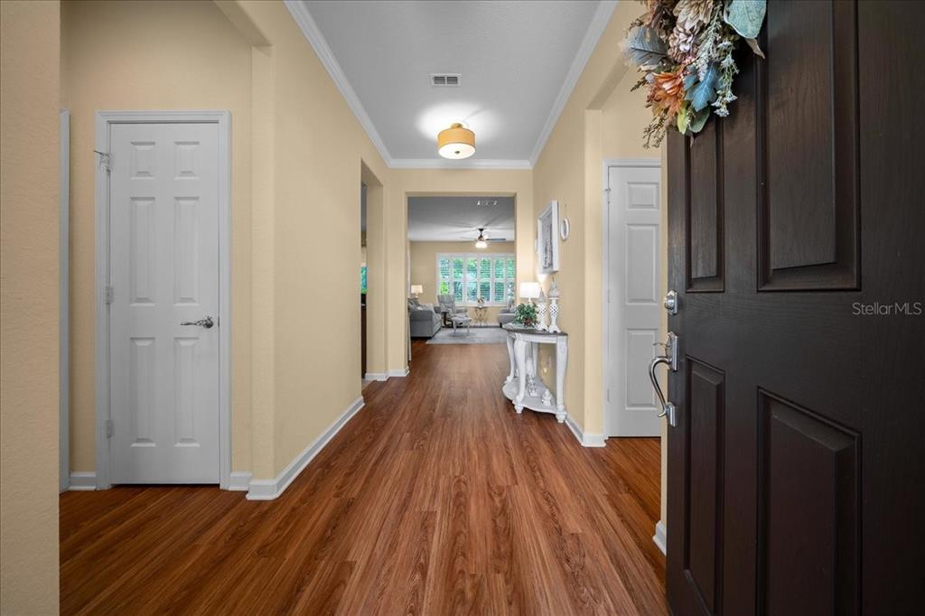 A view from an open front door into a hallway with wood-look flooring — 7393 SW 100TH COURT, OCALA, FL