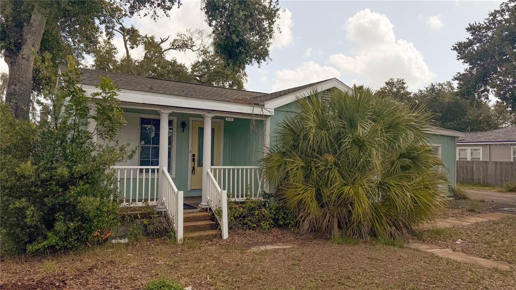 A light green house with a front porch and a large palm tree in front — 5045 38TH AVENUE N, ST PETERSBURG, FL