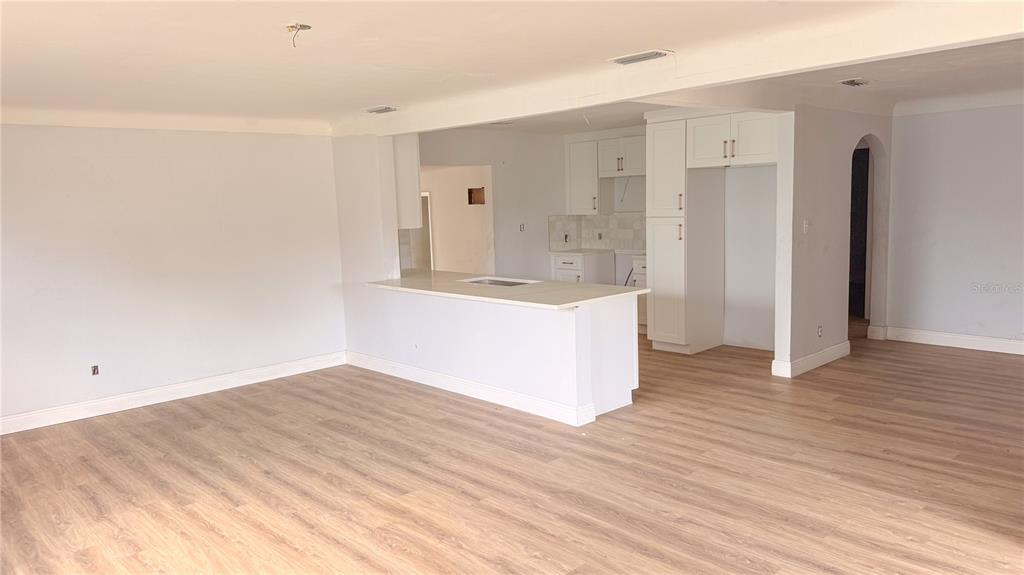 An open-concept living area features light wood-look flooring and a kitchen with white cabinets — 5045 38TH AVENUE N, ST PETERSBURG, FL