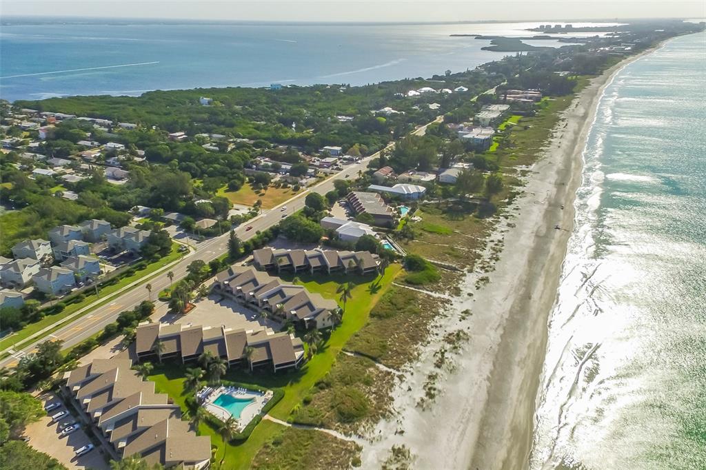 An aerial view of a coastal resort featuring beachfront condominiums, a swimming pool, and vegetation — 5655 GULF OF MEXICO DRIVE UNIT D107, LONGBOAT KEY, FL