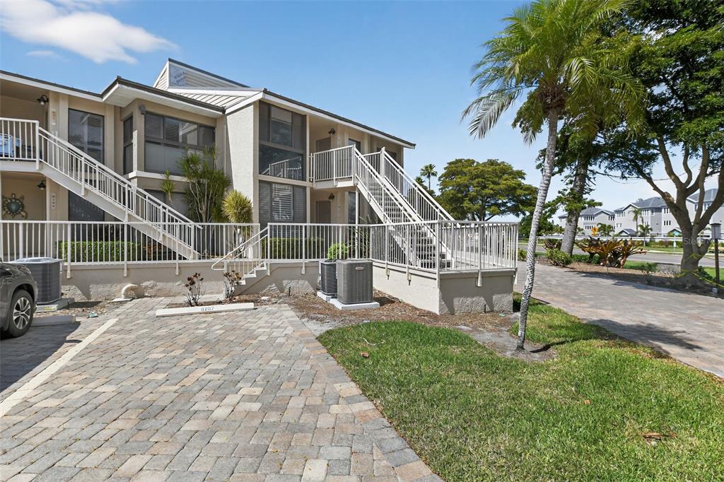 A two-story apartment building with exterior staircases, a paved parking area, and a palm tree — 5655 GULF OF MEXICO DRIVE UNIT D107, LONGBOAT KEY, FL