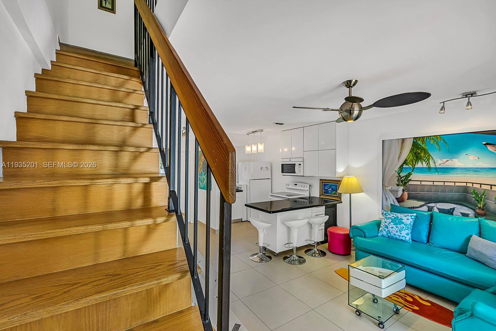 A wooden staircase leads down to a living area with a kitchen and turquoise sofa — 798 Crandon Blvd # C, Key Biscayne FL 33149, KEY BISCAYNE, FL