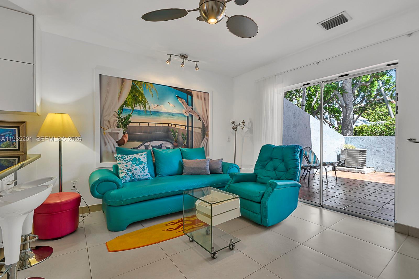 A living room features a turquoise sofa and recliner, a glass table, and a patio — 798 Crandon Blvd # C, Key Biscayne FL 33149, KEY BISCAYNE, FL
