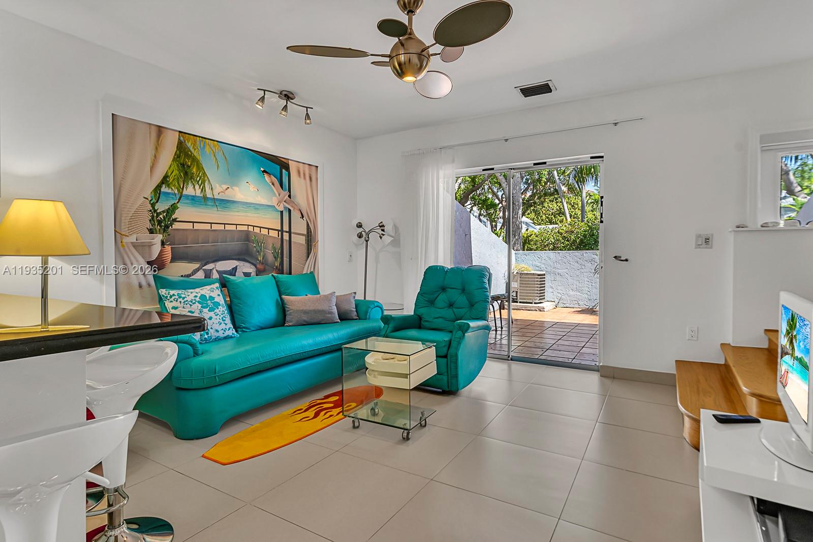 A living room features a turquoise sofa, matching recliner, tile flooring, and a sliding glass door — 798 Crandon Blvd # C, Key Biscayne FL 33149, KEY BISCAYNE, FL