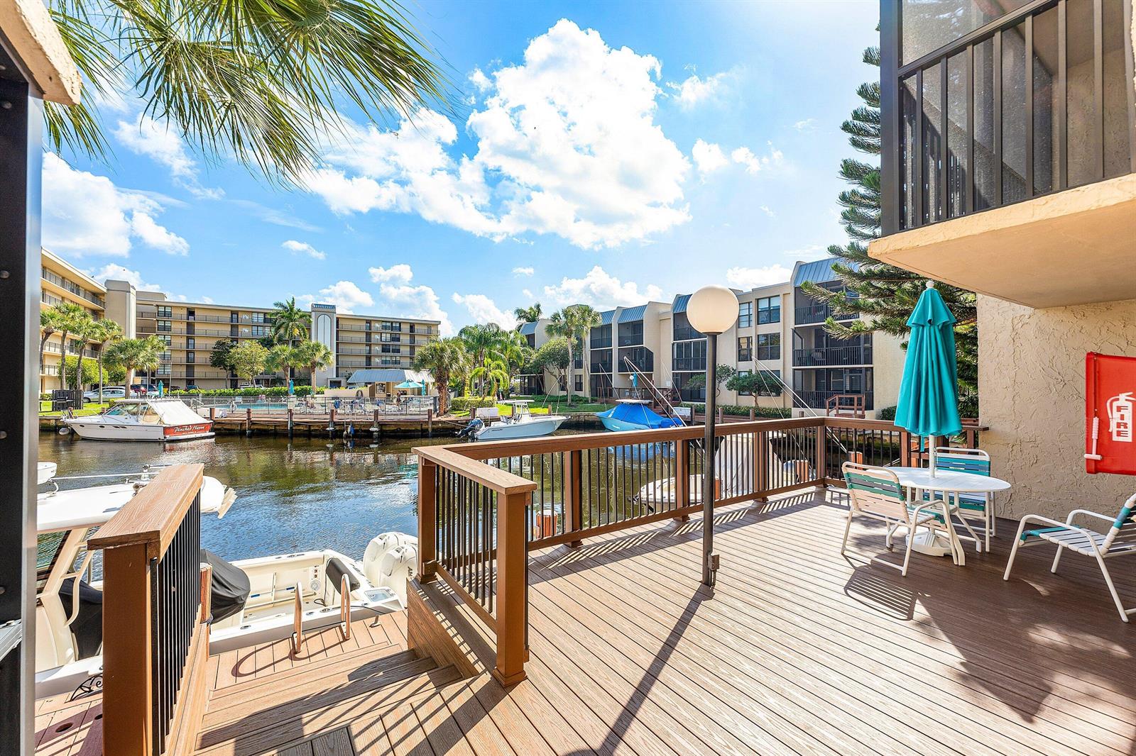 A wooden deck overlooks a canal with docked boats and multi-story apartment buildings — 10 Royal Palm Way # 203, Boca Raton FL 33432, BOCA RATON, FL