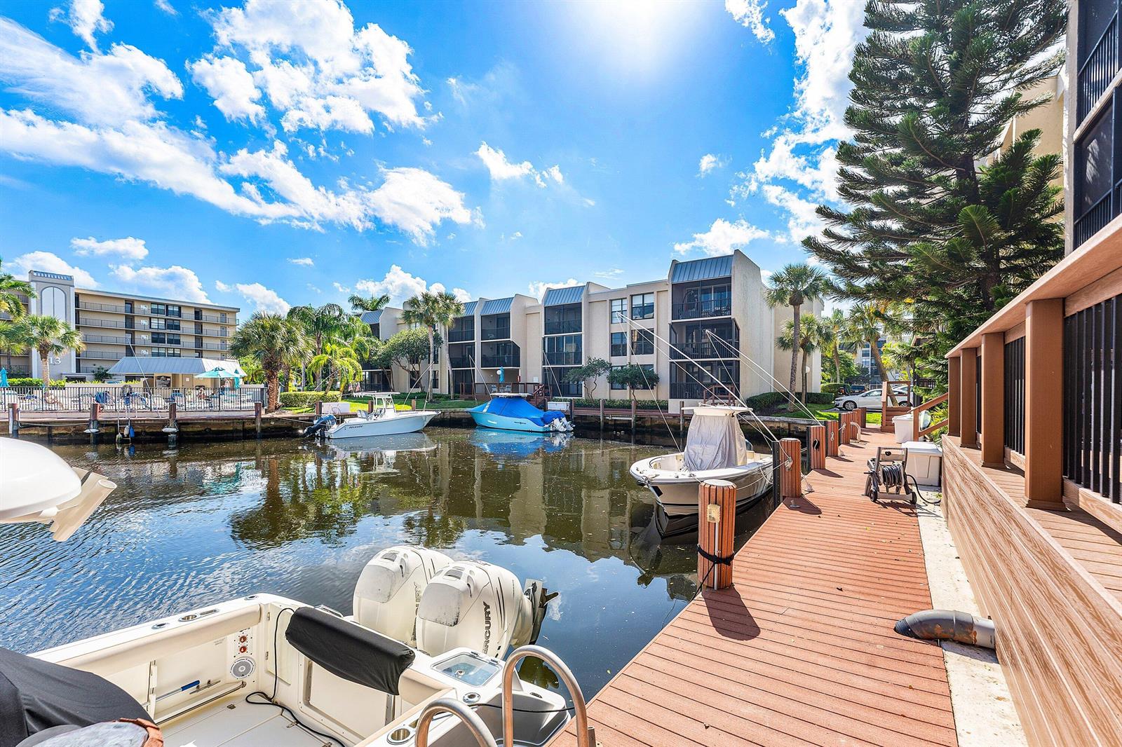 A wooden dock overlooks a canal with several boats moored in front of apartment buildings — 10 Royal Palm Way # 203, Boca Raton FL 33432, BOCA RATON, FL