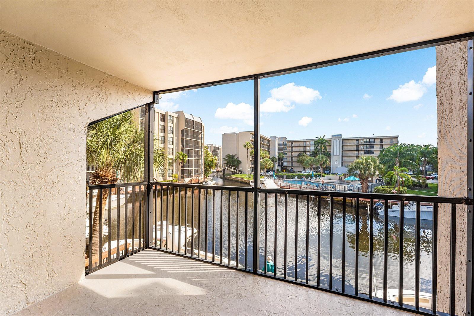 A screened-in balcony overlooks a canal with boats and a swimming pool area — 10 Royal Palm Way # 203, Boca Raton FL 33432, BOCA RATON, FL