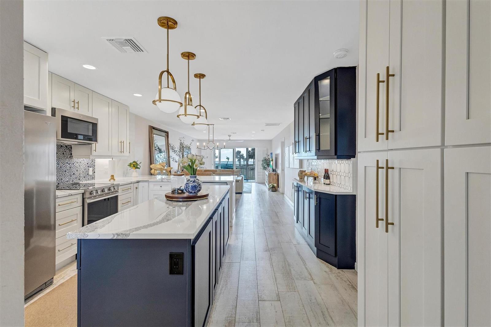 A kitchen with a blue island, white cabinets, gold hardware, and a view of the ocean — 7125 Gulf Of Mexico # 22, FL 34228, FL