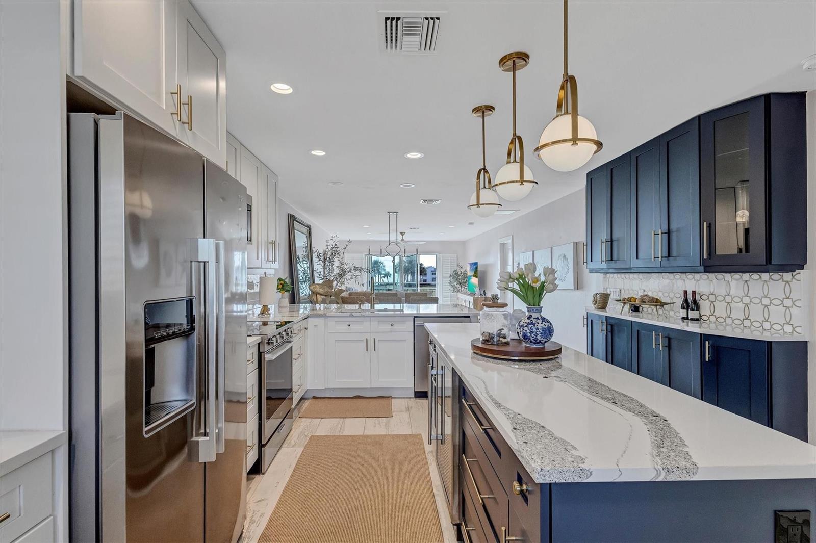 A kitchen features white and navy blue cabinetry, a stone island, and stainless steel appliances — 7125 Gulf Of Mexico # 22, FL 34228, FL