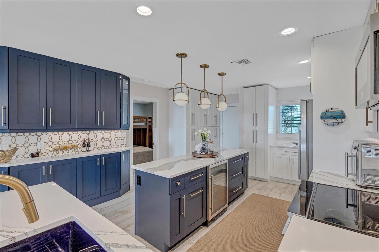 A modern kitchen features navy blue cabinets, a central island, and white quartz countertops — 7125 Gulf Of Mexico # 22, FL 34228, FL