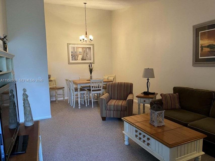 A living room and dining area featuring carpeted floors, neutral walls, and traditional furniture — 6327 Chasewood Dr # G, Jupiter FL 33458, JUPITER, FL