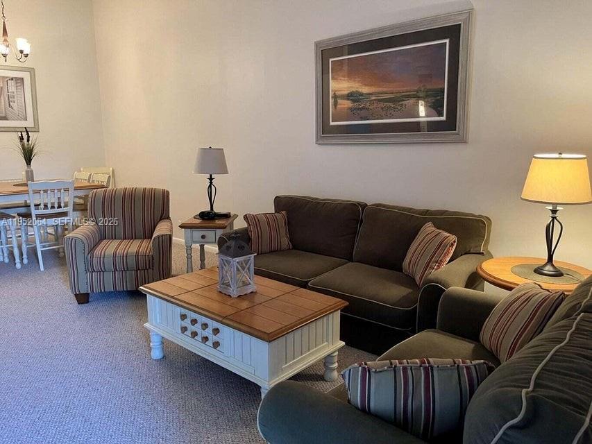 A living room features a brown sofa, a striped armchair, and a white coffee table — 6327 Chasewood Dr # G, Jupiter FL 33458, JUPITER, FL