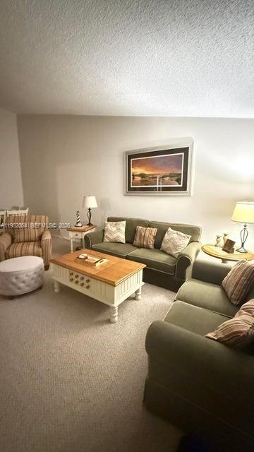 A living room features a green sofa, a matching armchair, and a wooden coffee table — 6327 Chasewood Dr # G, Jupiter FL 33458, JUPITER, FL