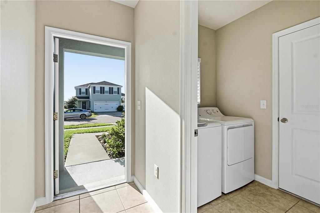 A laundry room with white appliances and tile flooring opens to an exterior view — 1530 FINNIGAN CIRCLE, HAINES CITY, FL