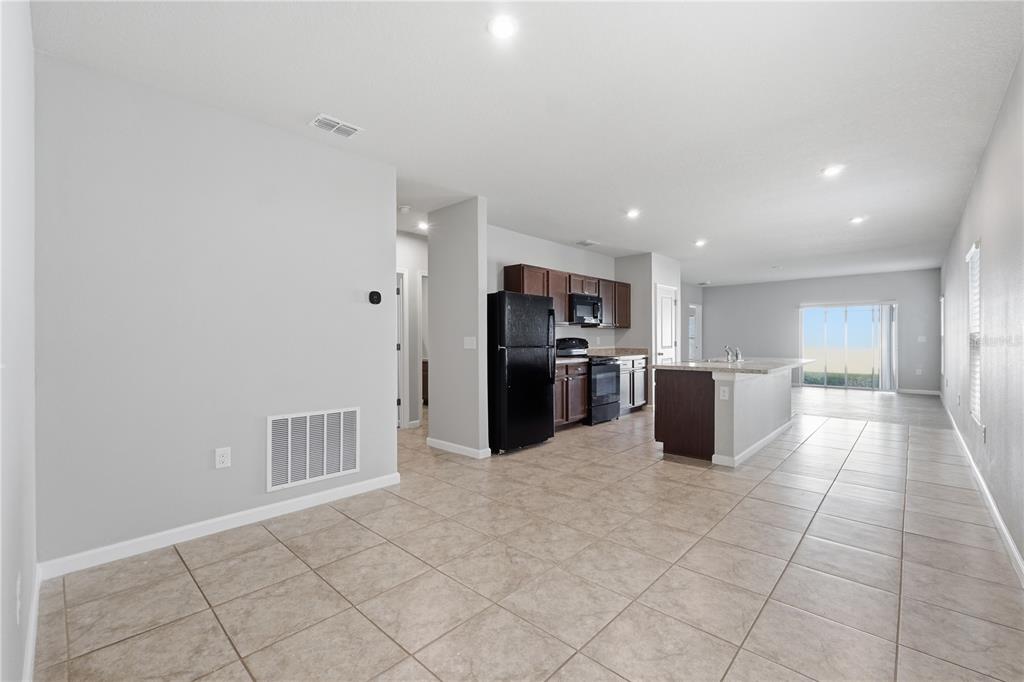 An open-concept kitchen and living area with tile flooring, dark cabinets, and a kitchen island — 1530 FINNIGAN CIRCLE, HAINES CITY, FL