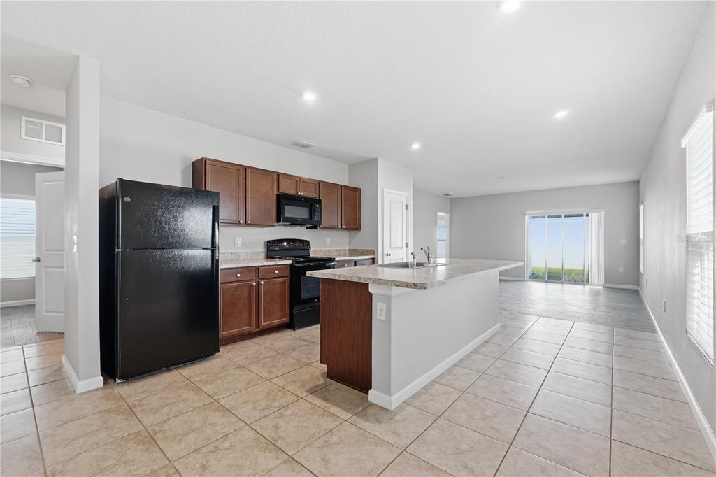 A kitchen with dark wood cabinets, black appliances, and a central island with a sink — 1530 FINNIGAN CIRCLE, HAINES CITY, FL