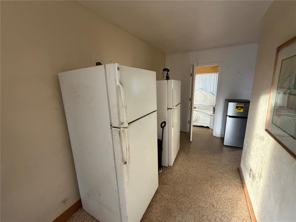 A room contains two white refrigerators and a smaller stainless steel refrigerator near a doorway — 30081 SW 148TH AVENUE, HOMESTEAD, FL