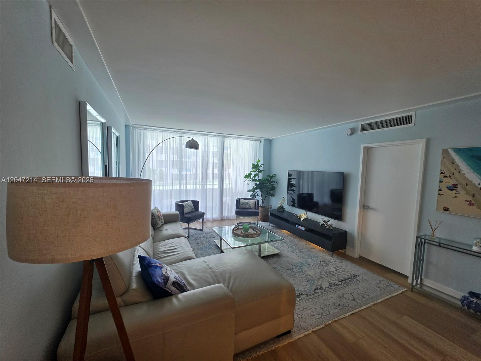 A living room features a sectional sofa, a glass coffee table, and a wall-mounted television — 5151 Collins Ave # 429, Miami Beach FL 33140, MIAMI BEACH, FL