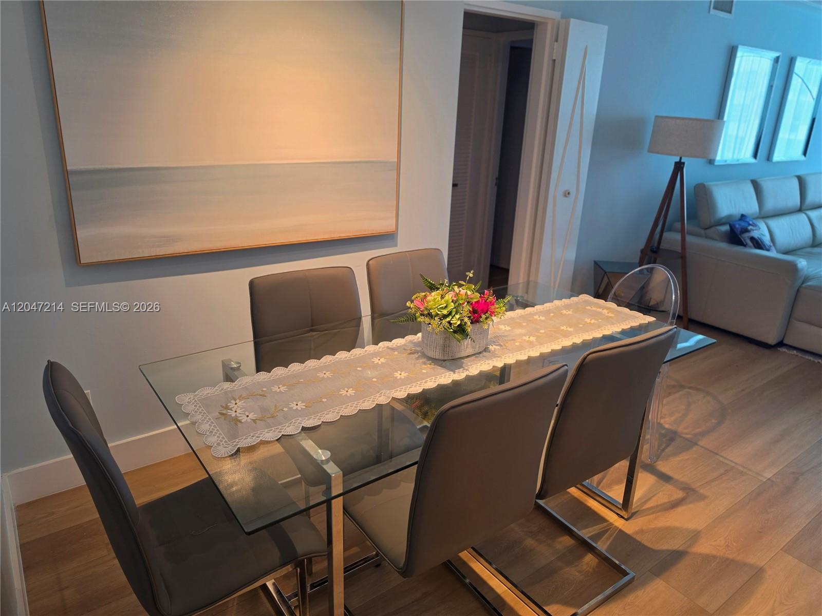 A dining room features a glass table with gray chairs and a floral table runner — 5151 Collins Ave # 429, Miami Beach FL 33140, MIAMI BEACH, FL