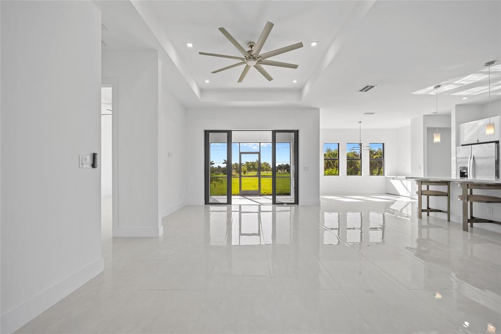 A bright, open-concept living area features white tile floors, a tray ceiling, and glass doors — 16322 NOGALES COURT, PUNTA GORDA, FL