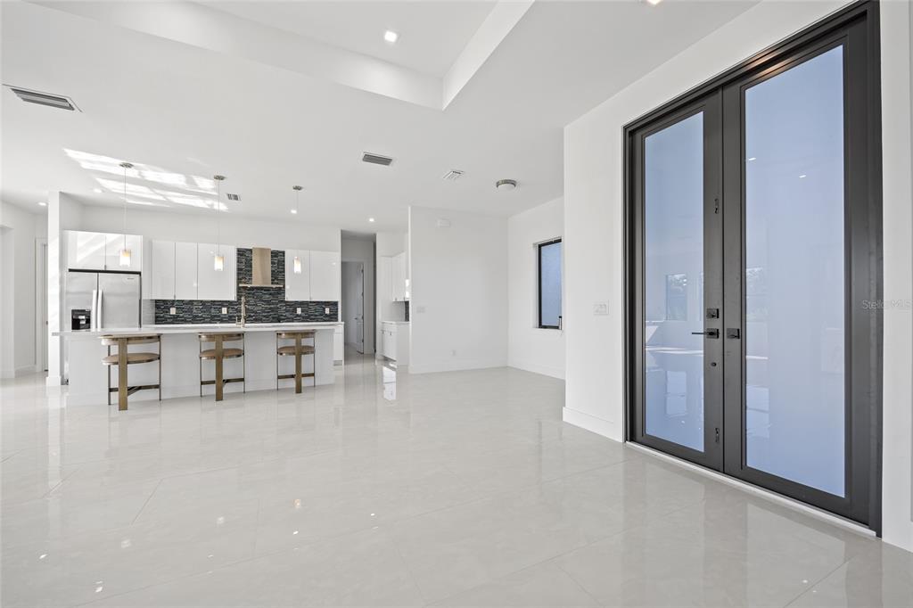 A modern kitchen with white cabinets and a breakfast bar opens into a spacious living area — 16322 NOGALES COURT, PUNTA GORDA, FL